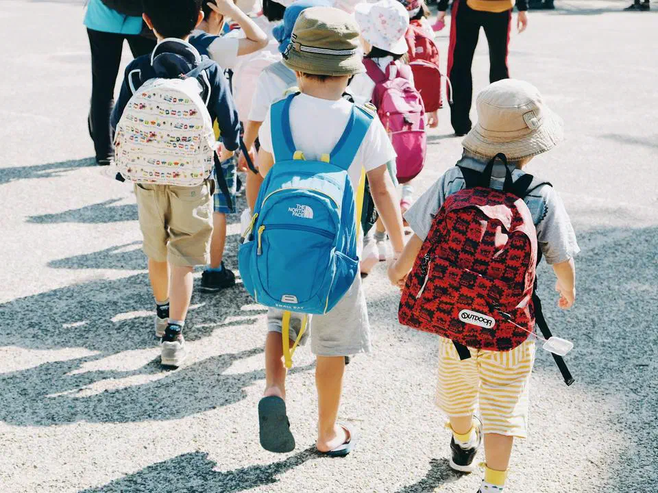 Children walking into school with backpacks at the start of a session